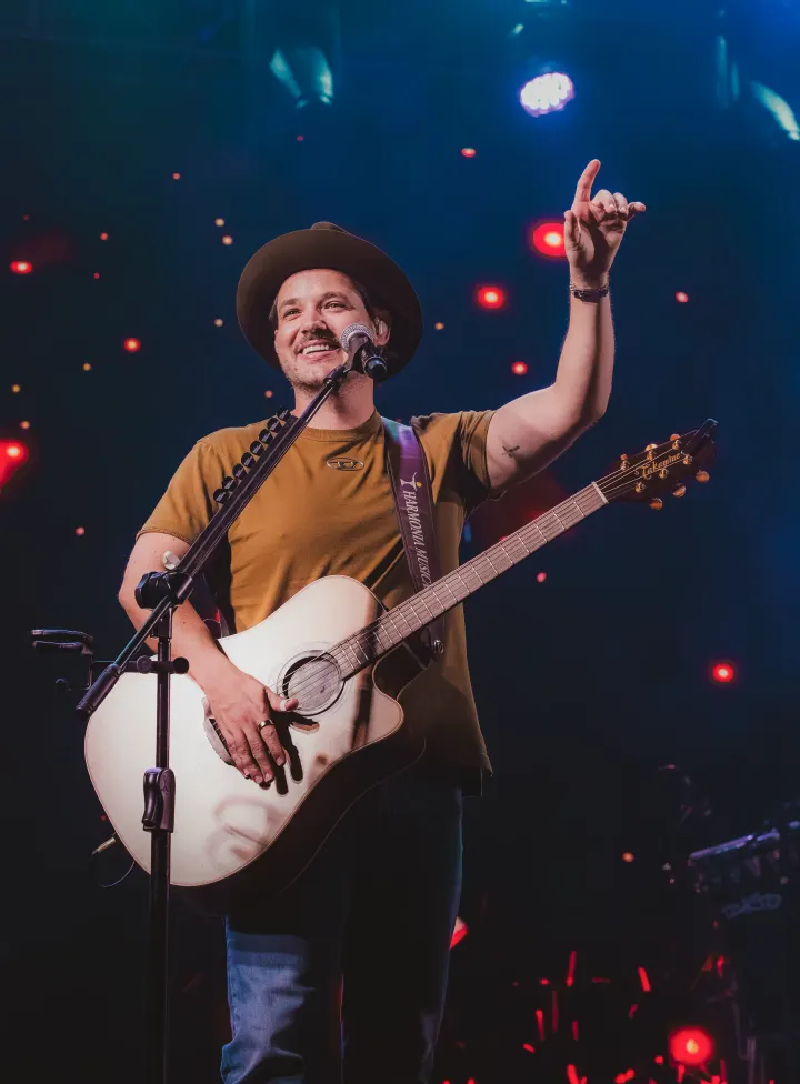 Israel Ribeiro cantando no palco de camiseta bege