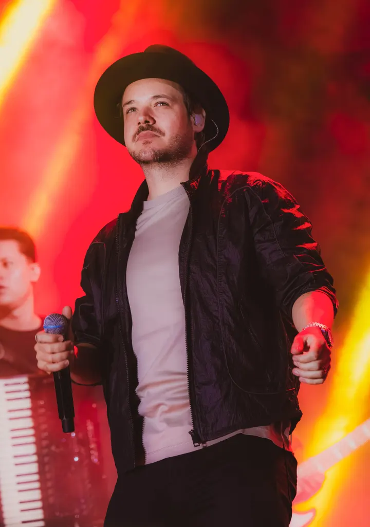 Israel Ribeiro em show sob luzes vermelhas e amarelas